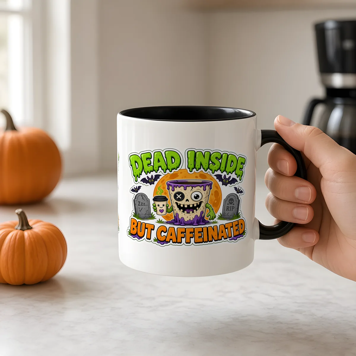 Dead Inside But Caffeinated Mug held by the handle in a bright kitchen with pumpkins and a coffee maker