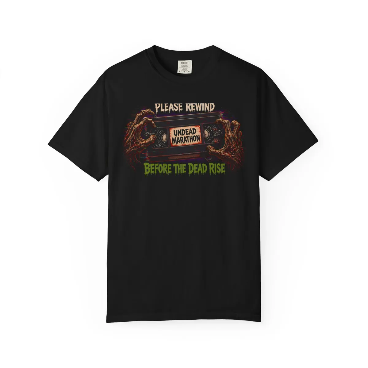 Please Rewind Before the Dead Rise VHS Tee: Original VHS cassette with a bone label reading UNDEAD MARATHON / HOME VIDEO · SP · T-120 · 1986 and retro red-orange-yellow stripes, RGB tracking-glitch bars, headline P