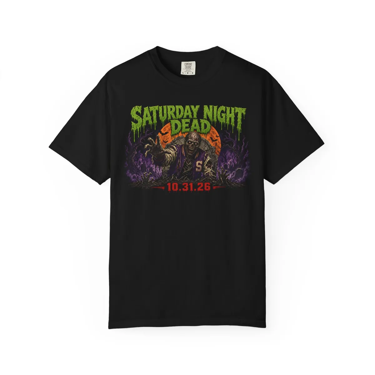 Saturday Night Dead 10.31.26 Tee: Full harvest moon with a black graveyard silhouette (dead tree, tombstones, two zombie hands) cut into it, purple bats, stacked type: SATURDAY (Anton, bone), NIGHT DEAD (